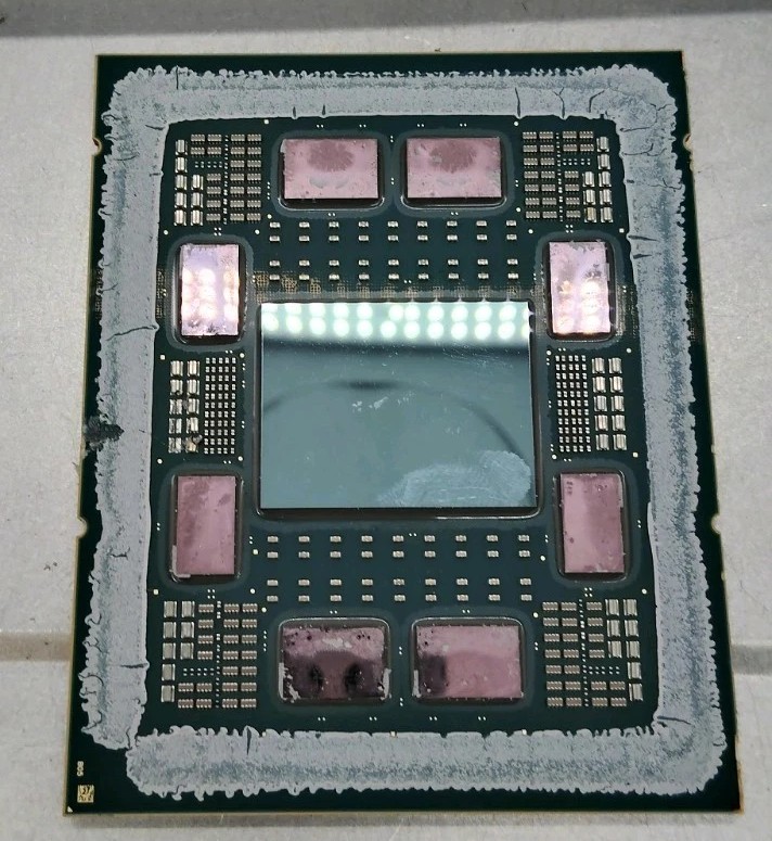 An AMD EPYC 9004-series processor with its lid removed: a large I/O die in the centre, ringed by eight smaller compute chiplets on a dark substrate.